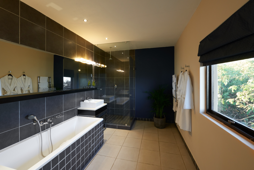 The navy blue King Room Mountain View hotel bathroom with a large window, with a shower, bath and basin.