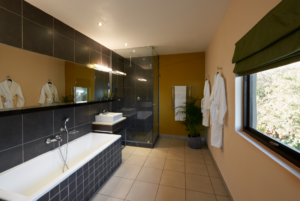The King Room Garden View bathroom with black titles a shower, towel rack, window and sink