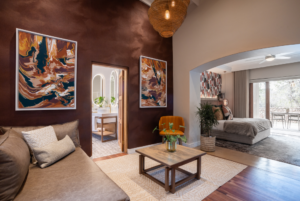 The sitting area of the Superior King Suite hotel room. There is a couch with two cream pillows in the corner with a coffee table in front. To the right is a bed.