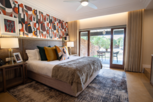 Superior King Suite hotel room with a large king-sized bed with many pillows and connect patio by wooden sliding doors. On the patio there is a patio furniture set.