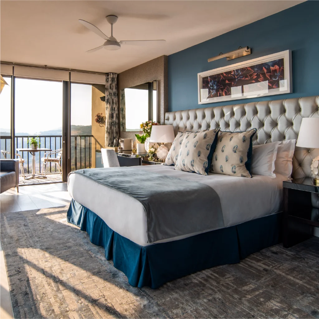 Spacious bedroom with a large bed, elegant decor, and a panoramic view through sliding glass doors. The room feels bright, luxurious, and inviting.